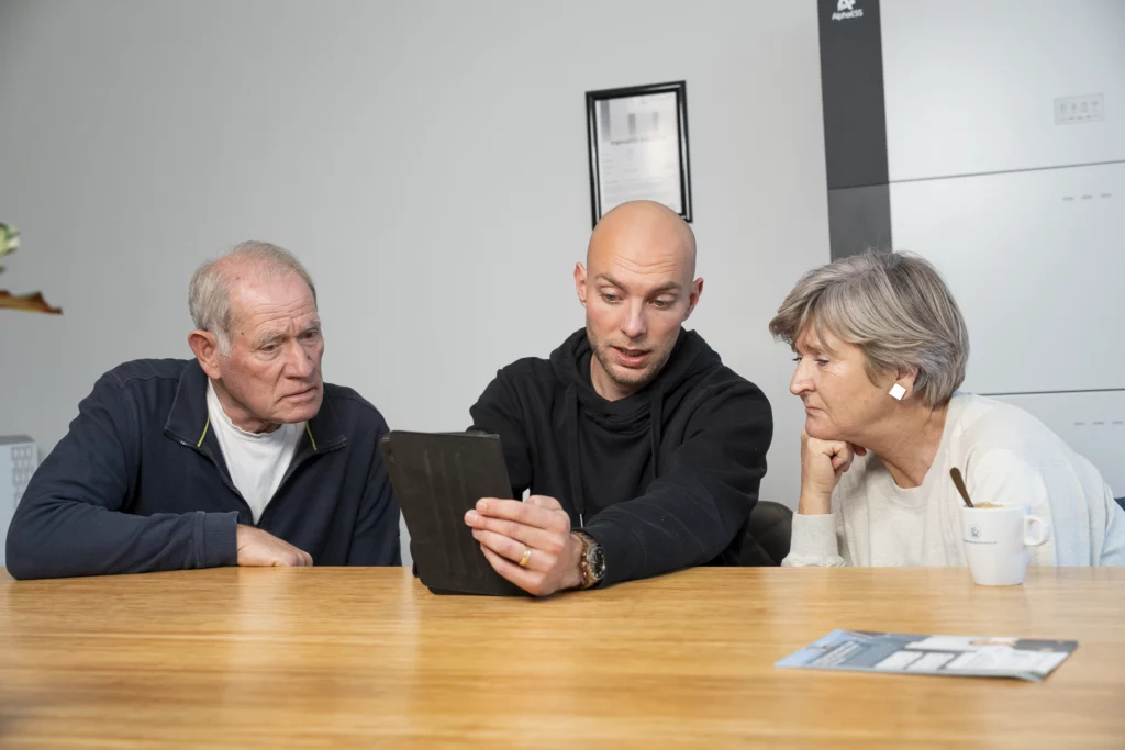 Adviseur Dion bekijkt samen met klanten een thuisbatterij op de tablet in de showroom