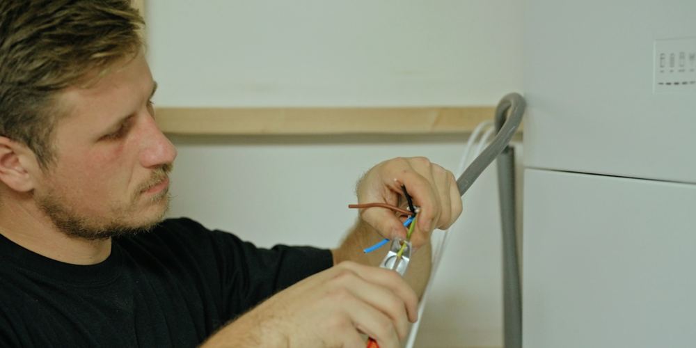 Monteur stript een kabel tijdens de installatie