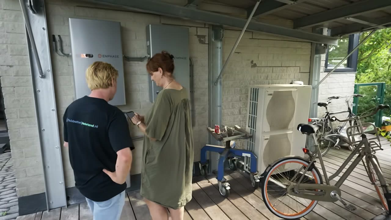 Britta en Freek bekijken de app bij de drie Enphase-batterijen